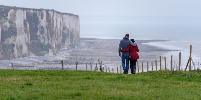 Sur le sentier du littoral, un couple se promène observant la vue sur les falaises de craie.