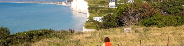 Randonneuse, sur le sentier du littoral, regardant le point de vue sur les falaises depuis les hauteurs du Bois de Cise