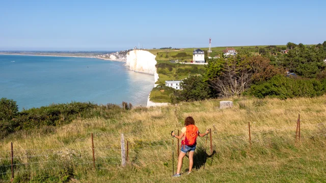 Randonneuse, sur le sentier du littoral, regardant le point de vue sur les falaises depuis les hauteurs du Bois de Cise