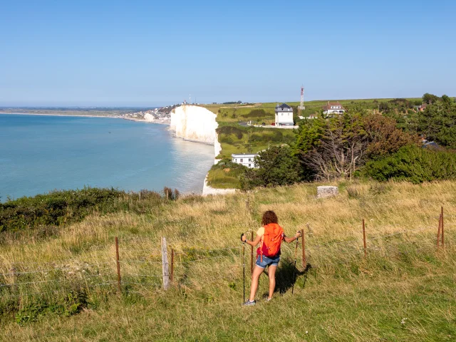 Randonneuse, sur le sentier du littoral, regardant le point de vue sur les falaises depuis les hauteurs du Bois de Cise