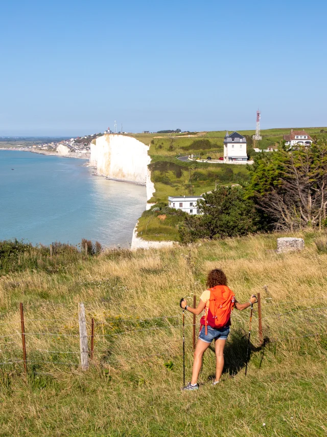 Randonneuse, sur le sentier du littoral, regardant le point de vue sur les falaises depuis les hauteurs du Bois de Cise