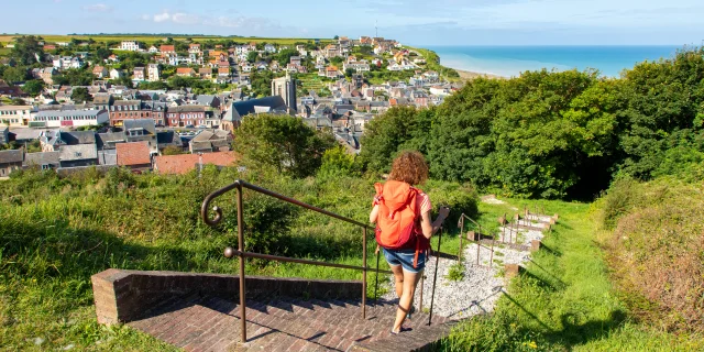 Randonneuse à Ault, descendant les marches de la Porte du Moulinet, profitant du panorama qui d'offre à elle sur le centre-ville et la mer.