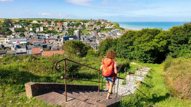 Randonneuse à Ault, descendant les marches de la Porte du Moulinet, profitant du panorama qui d'offre à elle sur le centre-ville et la mer.