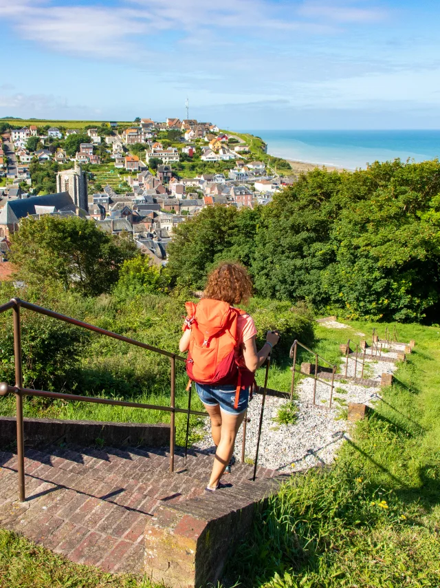 Randonneuse à Ault, descendant les marches de la Porte du Moulinet, profitant du panorama qui d'offre à elle sur le centre-ville et la mer.