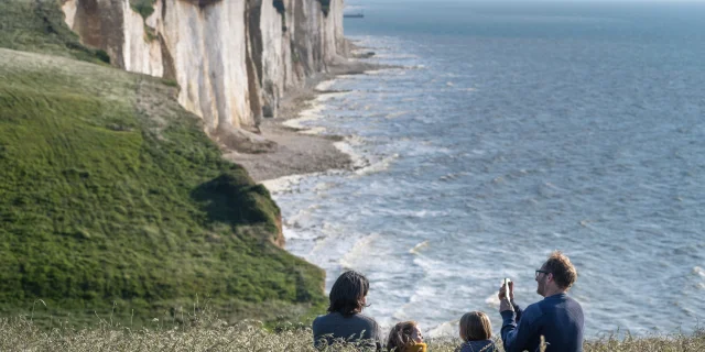 Une famille profitant du panorama sur le sentier du littoral pour faire une pause dans les champs